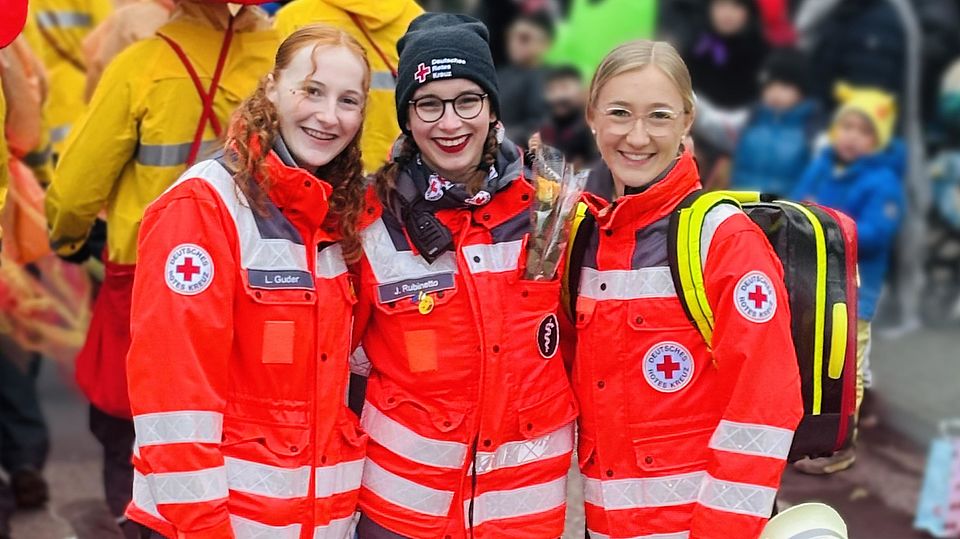 3 Einsatzkräfte stehen zusammen an Karneval und lächeln in die Kamera